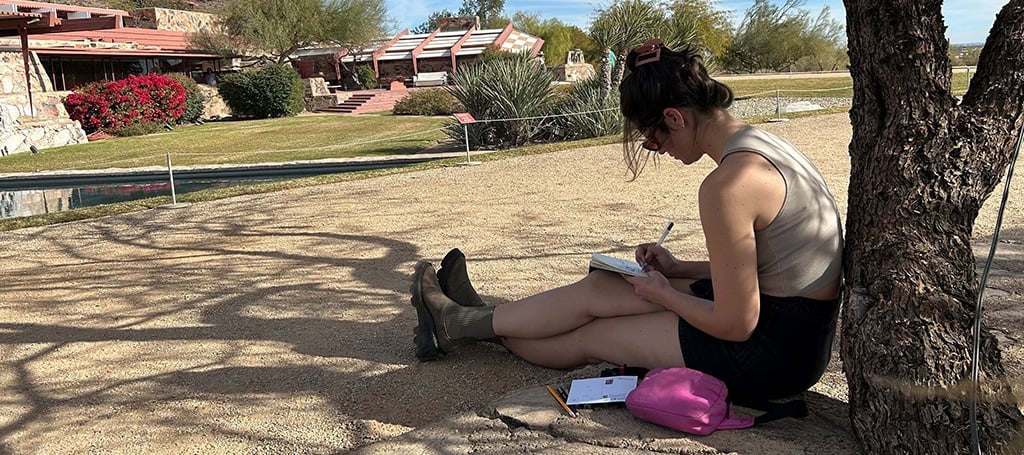 Artist sitting under a tree drawing at Taliesin West