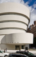Exterior view of the Solomon R. Guggenheim Museum in New York City, showcasing its distinctive spiral design and modernist architecture with a clear blue sky in the background.