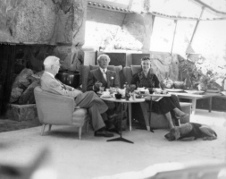 Frank Lloyd Wright, Oglivanna Lloyd Wright have tea with a guest with a dog laying next to Oglivanna.