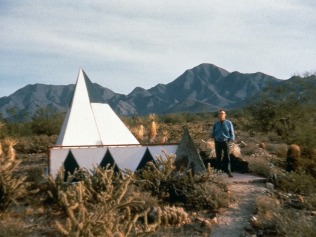 David Dodge in the Sonoran desert standing next to his the triangular tent.