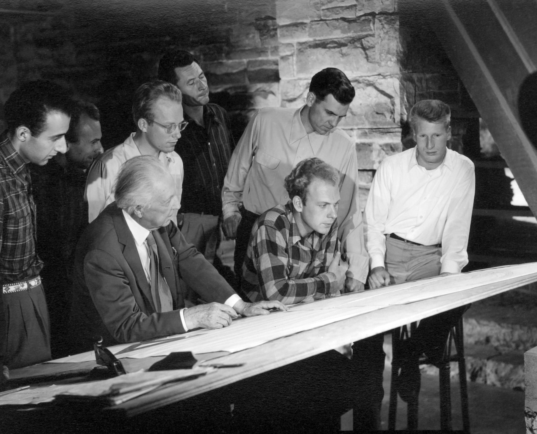 Frank Lloyd Wright with apprentices of the Taliesin Fellowship in 1955 at the Hillside studio at Taliesin.Seated from left: Frank Lloyd Wright, Eric Lloyd Wright. Standing from left: John Amarantides, Joe Fabris, David Dodge, Kenn Lockhart, Tom Casey, Donald Brown.