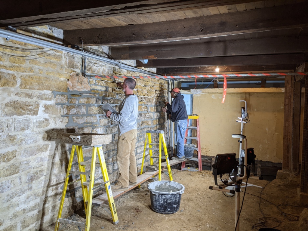 Preservation team members repointing stone walls in the Hillside Theatre basement