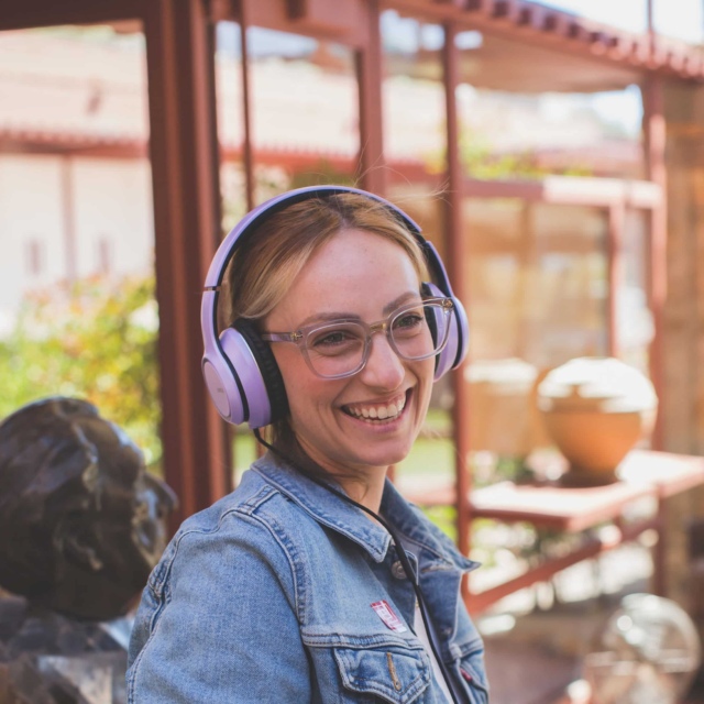 A visitor on the Self-Guided Audio Tour, wearing headphones, stands in the Garden Room at Taliesin West, learning about its history and Frank Lloyd Wright's personal items on display.