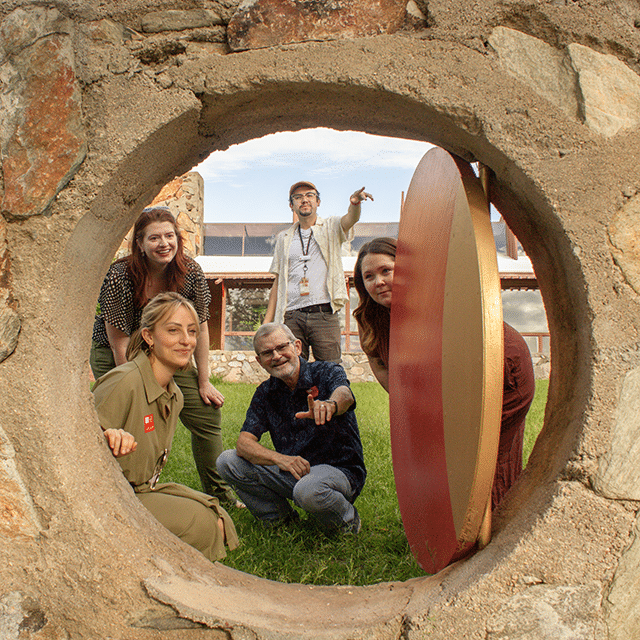 A group of visitors on a Behind-The-Scenes Guided Tour enjoying a rare view of the Moon Gate doorway opening, revealing more of the property at Taliesin West. 