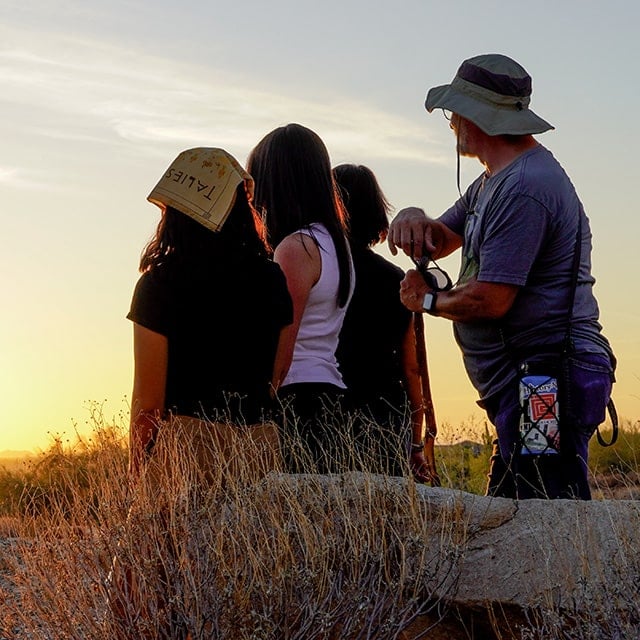 Guest take a moment to view the sun setting over the Sonoran Desert on a Golden Hour Sunset Hike at Taliesin West.