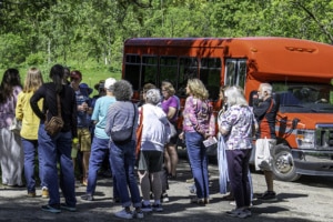 Guests on a tour of Taliesin with red tour bus